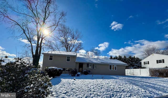 snow covered house featuring fence