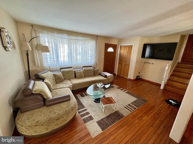 living area featuring dark wood-style flooring, stairway, and baseboards