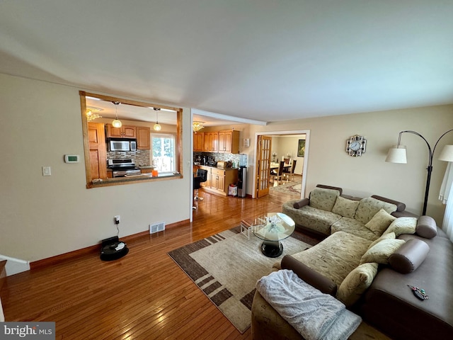 living room with wood finished floors, visible vents, and baseboards