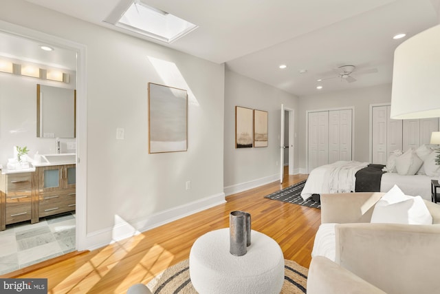 bedroom featuring light hardwood / wood-style floors, multiple closets, and a skylight