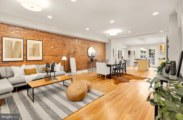 living room with light hardwood / wood-style floors and brick wall