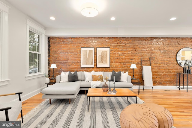 living room with light hardwood / wood-style floors and brick wall