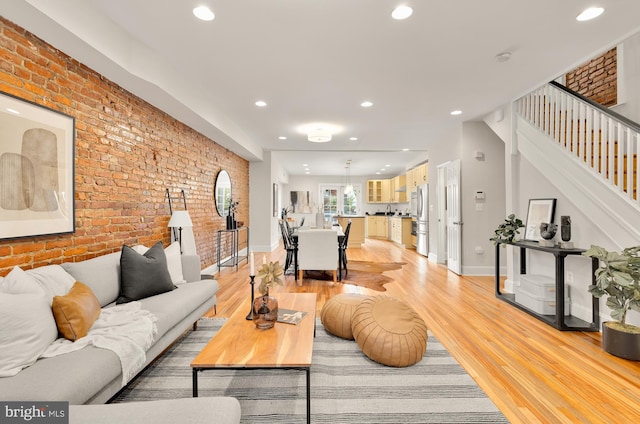 living room featuring brick wall and light hardwood / wood-style floors