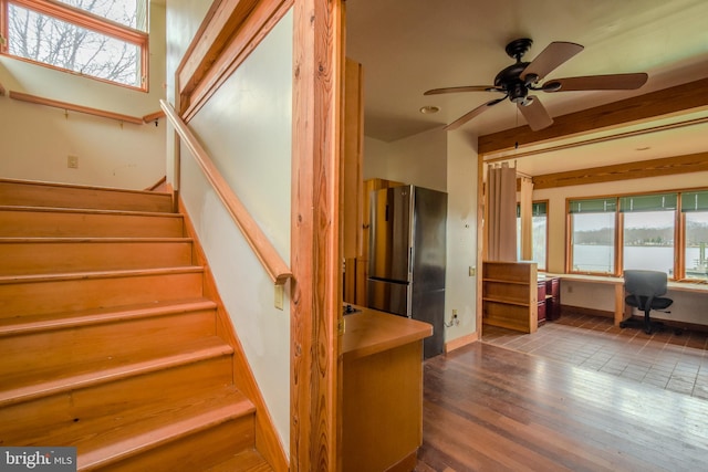 stairway with wood finished floors, ceiling fan, and baseboards