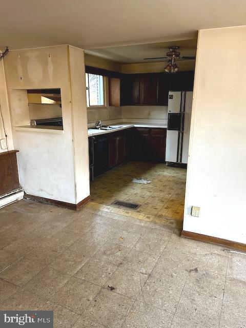 kitchen with dark brown cabinetry, white fridge, ceiling fan, and sink