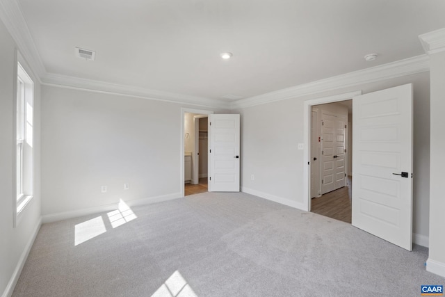 unfurnished bedroom with crown molding, ensuite bathroom, and light colored carpet