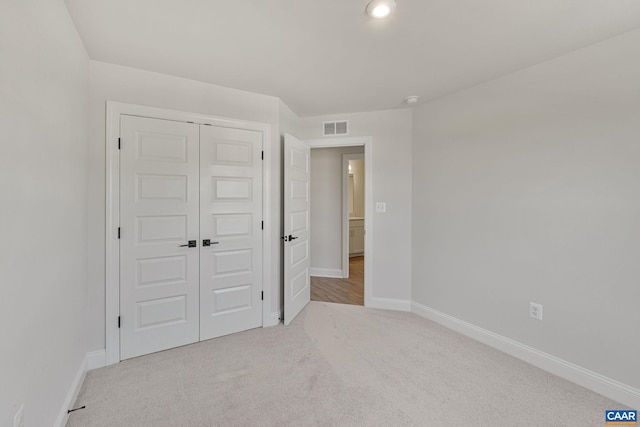 unfurnished bedroom with a closet and light colored carpet