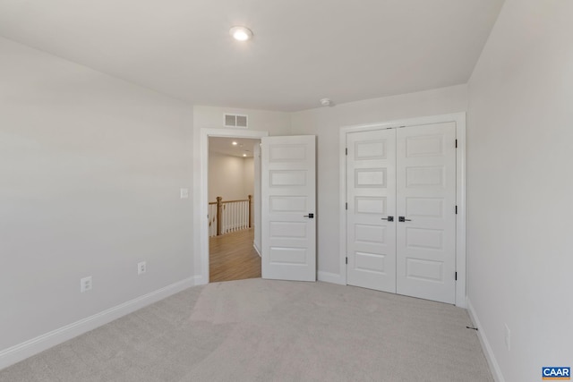 unfurnished bedroom featuring light carpet and a closet