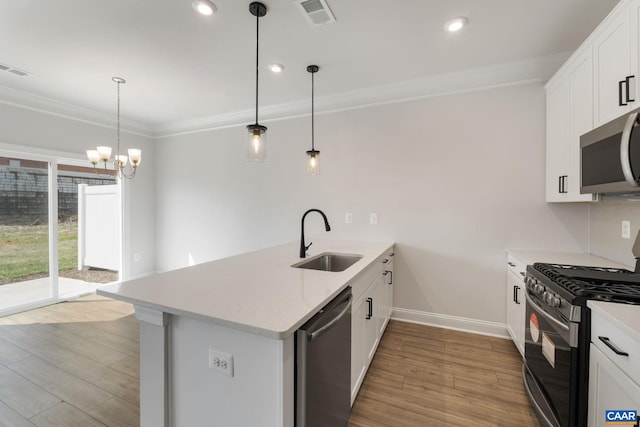 kitchen featuring kitchen peninsula, stainless steel appliances, sink, an inviting chandelier, and white cabinetry