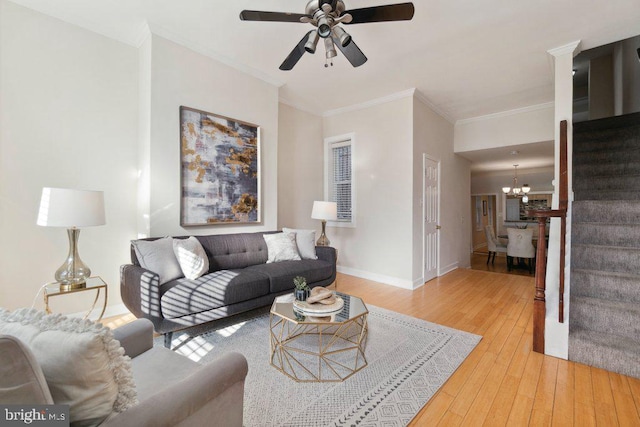 living room with hardwood / wood-style floors, ceiling fan with notable chandelier, and crown molding