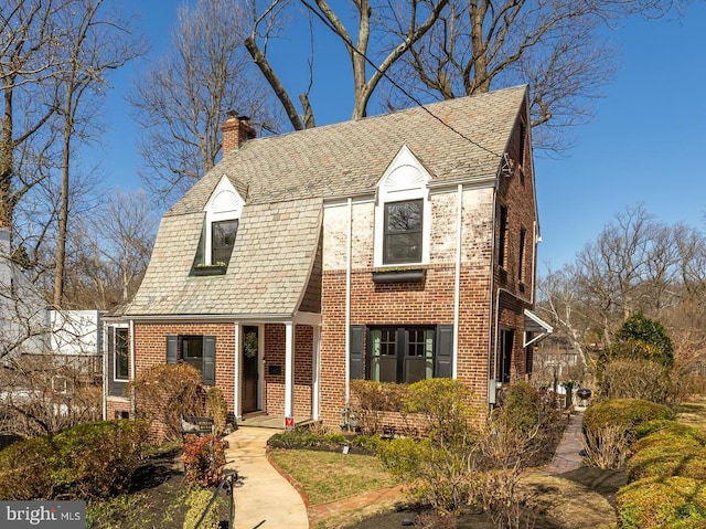 view of front of property with brick siding, a high end roof, and a chimney