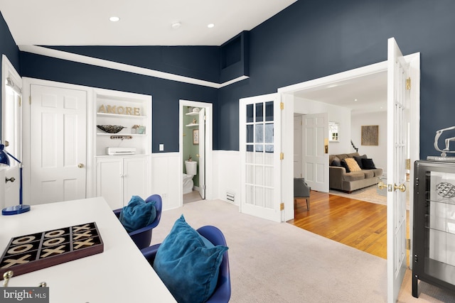 carpeted home office featuring wood finished floors, recessed lighting, french doors, wainscoting, and lofted ceiling