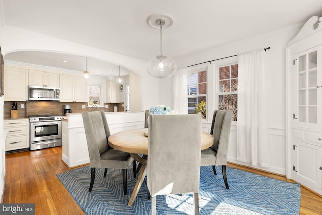 dining space with arched walkways, hardwood / wood-style floors, and crown molding