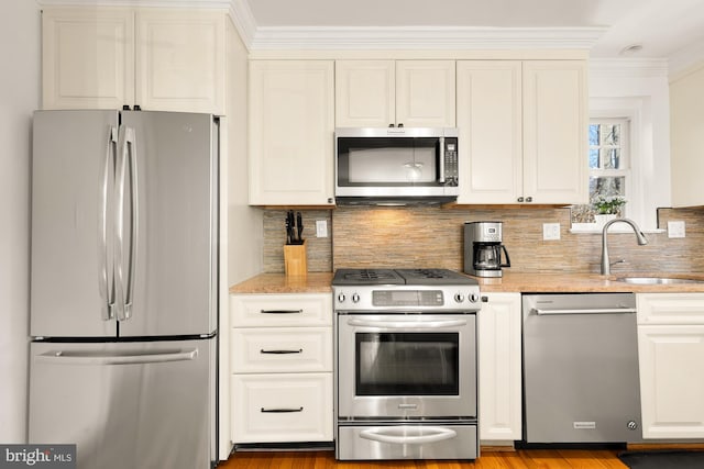 kitchen featuring a sink, light stone counters, stainless steel appliances, white cabinets, and decorative backsplash