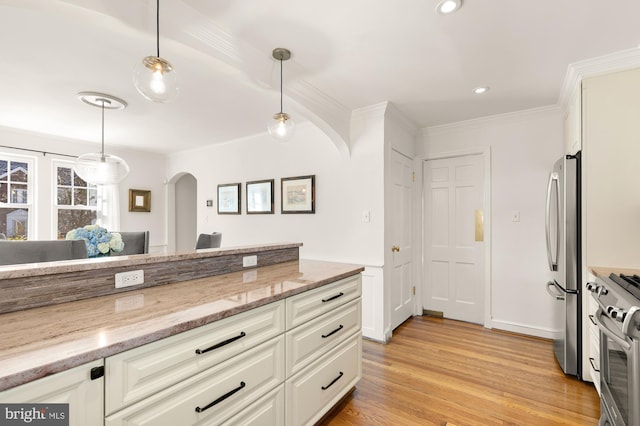 kitchen with decorative light fixtures, light wood-style flooring, appliances with stainless steel finishes, and white cabinets