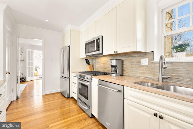 kitchen with a sink, ornamental molding, a wealth of natural light, and stainless steel appliances