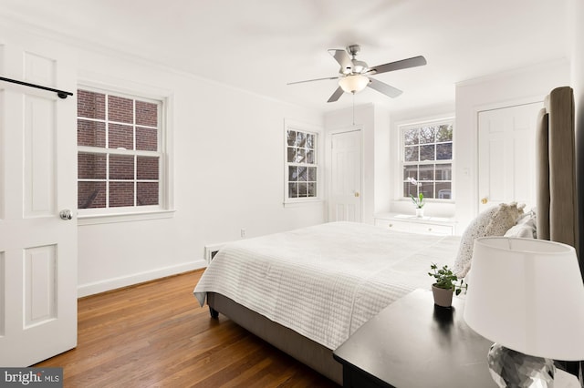 bedroom with a ceiling fan, crown molding, wood finished floors, and baseboards