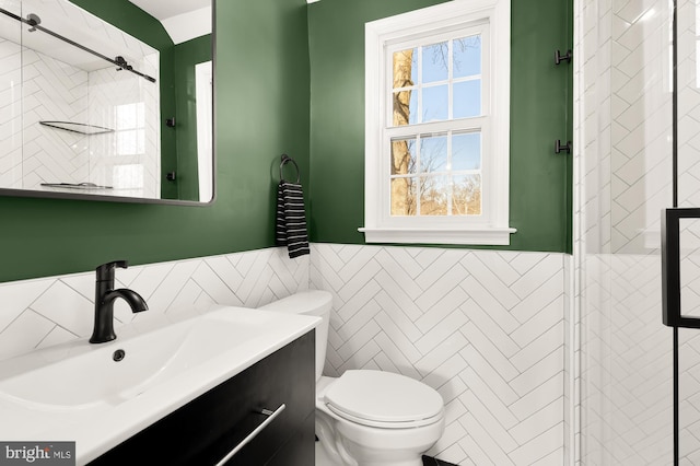 bathroom featuring toilet, tile walls, wainscoting, and vanity