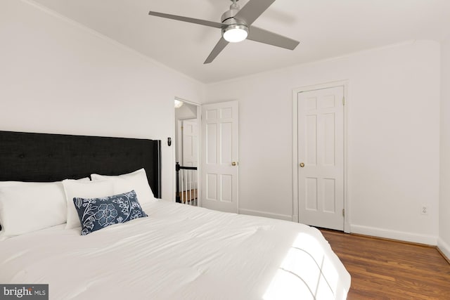 bedroom featuring baseboards, a ceiling fan, wood finished floors, and crown molding