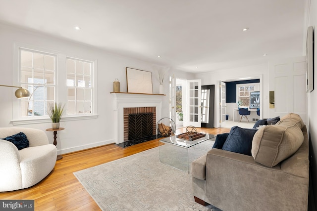 living room with a brick fireplace, recessed lighting, wood finished floors, and baseboards