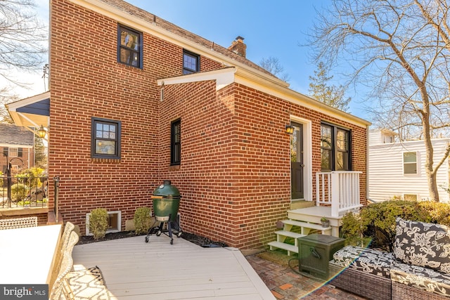 rear view of house featuring a wooden deck and brick siding