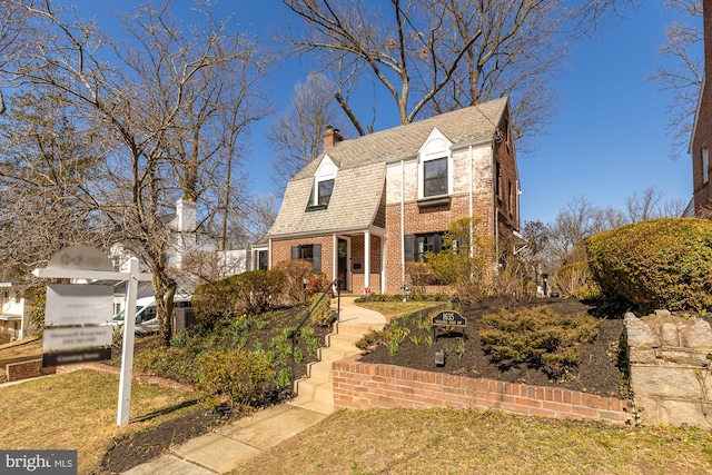 colonial inspired home featuring brick siding and a chimney