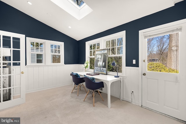 carpeted office with a wealth of natural light, a wainscoted wall, and lofted ceiling with skylight