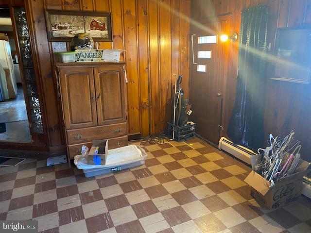 entryway featuring a baseboard radiator, light floors, and wooden walls