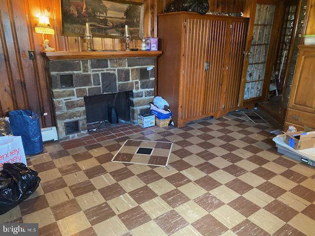 unfurnished living room featuring tile patterned floors, a stone fireplace, and wood walls