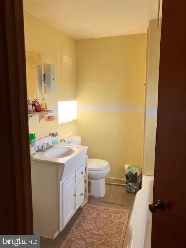 full bath with tile patterned flooring, toilet, vanity, and a tub