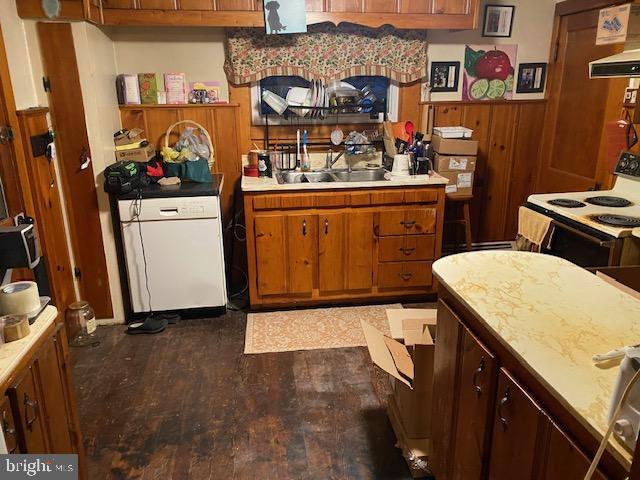 kitchen with dark wood-type flooring, refrigerator, sink, wooden walls, and extractor fan