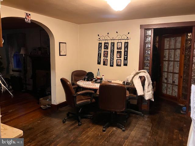 dining room with arched walkways and wood finished floors