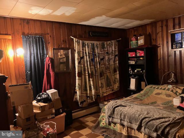 bedroom featuring tile patterned floors, baseboard heating, and wood walls