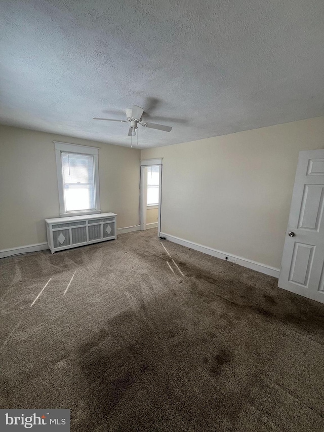 empty room featuring a textured ceiling, radiator, carpet floors, and ceiling fan