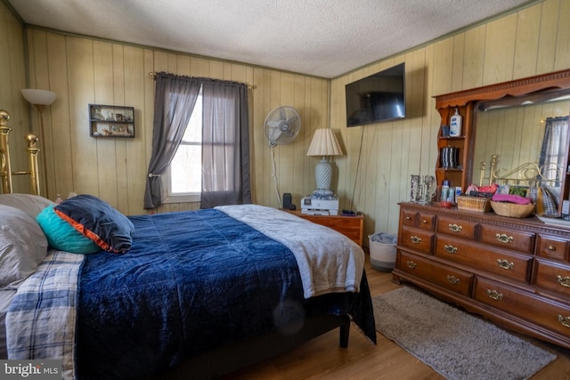 bedroom with hardwood / wood-style floors, a textured ceiling, and wood walls