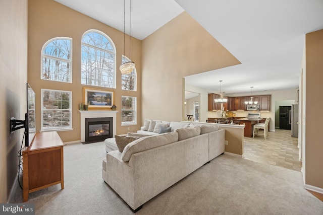 carpeted living room featuring a chandelier and a high ceiling