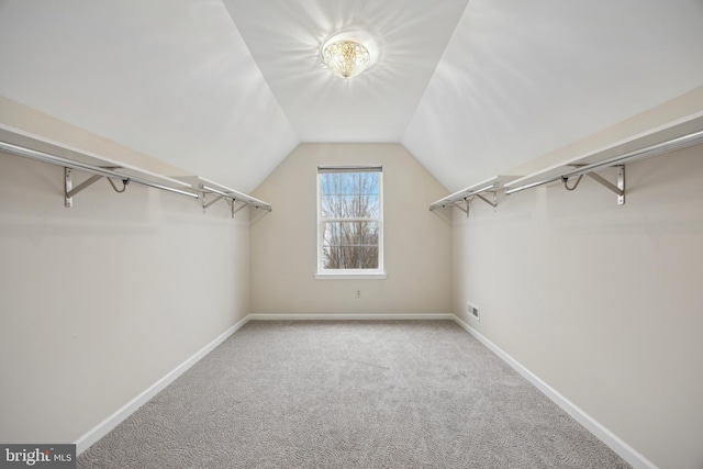 spacious closet with light carpet and vaulted ceiling