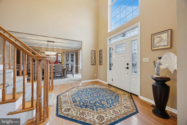 foyer with a towering ceiling, a chandelier, and hardwood / wood-style flooring