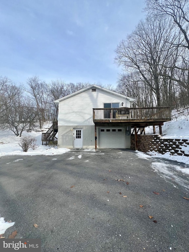 view of snowy exterior with a garage and a wooden deck