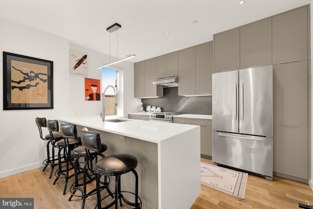 kitchen featuring kitchen peninsula, a kitchen bar, gray cabinets, appliances with stainless steel finishes, and sink