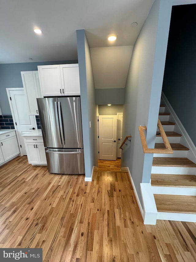 kitchen featuring white cabinetry, baseboards, light countertops, freestanding refrigerator, and light wood finished floors