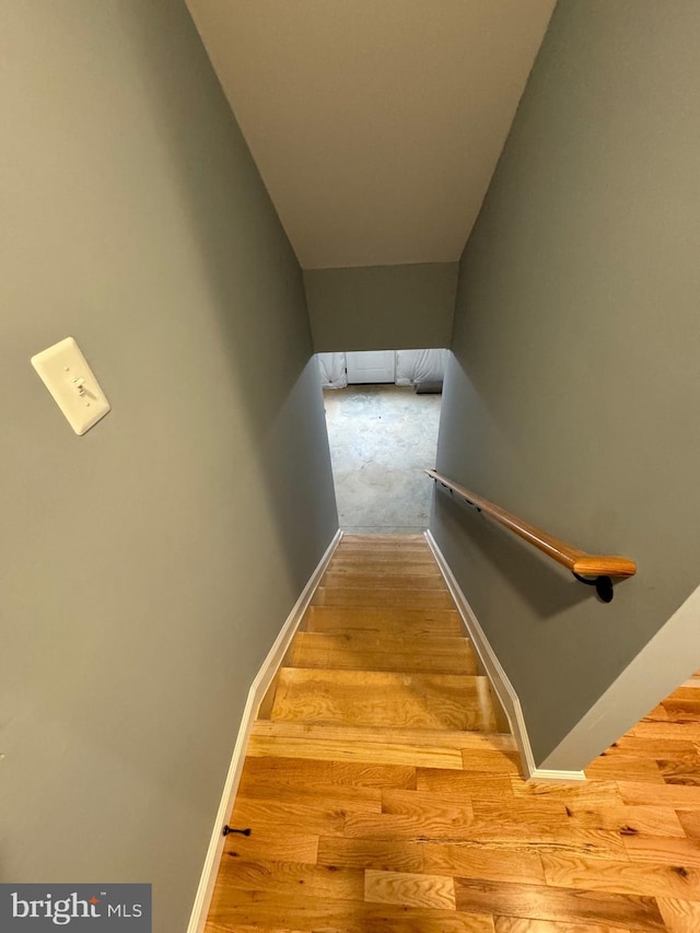 staircase featuring wood finished floors and baseboards