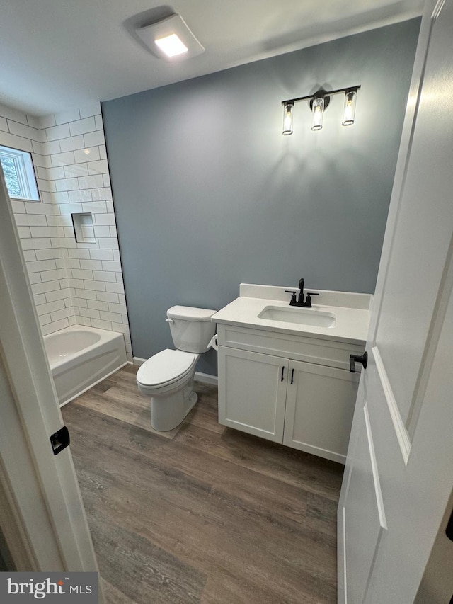 full bath featuring baseboards, toilet, wood finished floors, tub / shower combination, and vanity