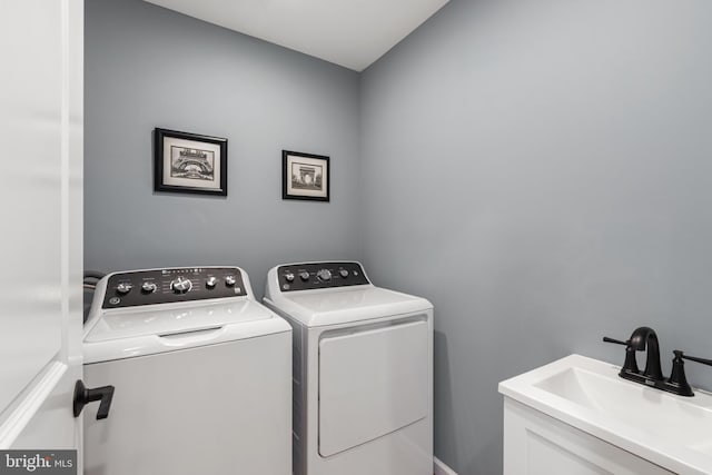 laundry area with laundry area, separate washer and dryer, and a sink