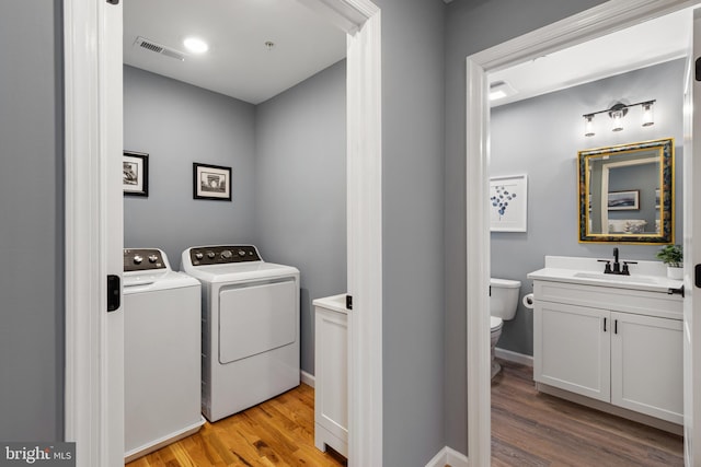 laundry area featuring laundry area, visible vents, light wood-style floors, separate washer and dryer, and a sink