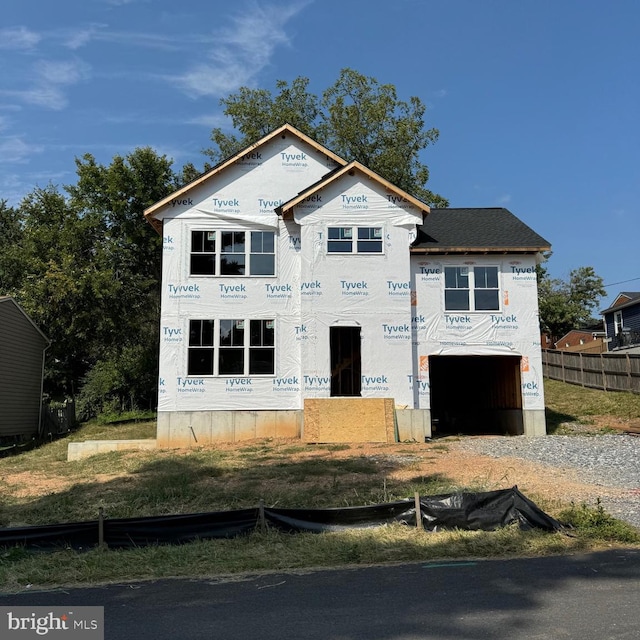 unfinished property with driveway, an attached garage, and fence