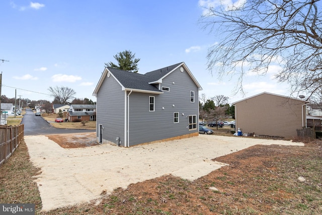 rear view of property featuring roof with shingles and fence