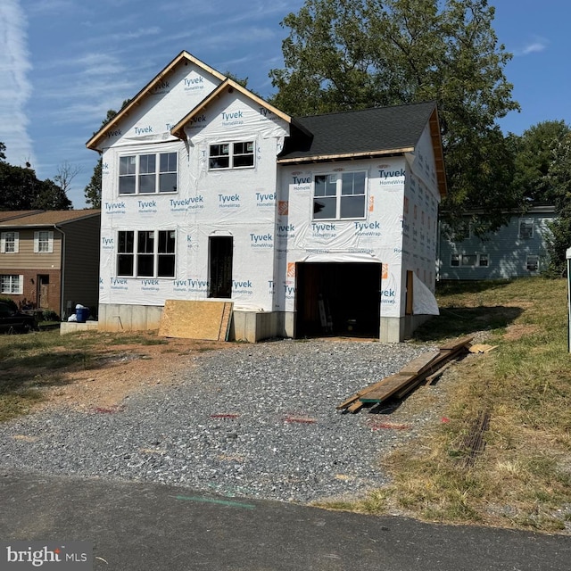 unfinished property with gravel driveway and a garage