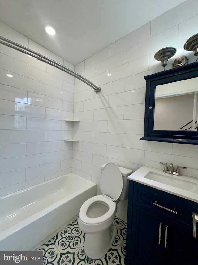 full bathroom featuring tiled shower / bath combo, tile patterned flooring, toilet, vanity, and tile walls