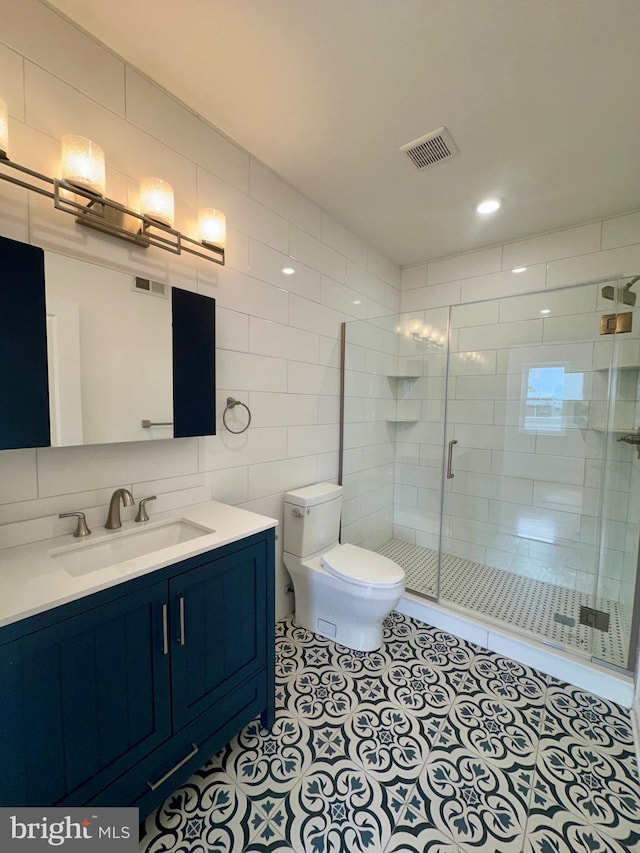 bathroom with tile patterned flooring, an enclosed shower, toilet, vanity, and tile walls